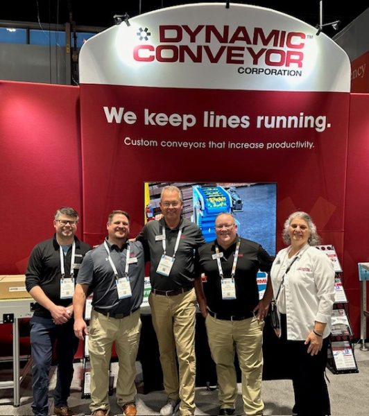 Dynamic Conveyor staff standing in front of their 2024 Pack Expo booth in Chicago