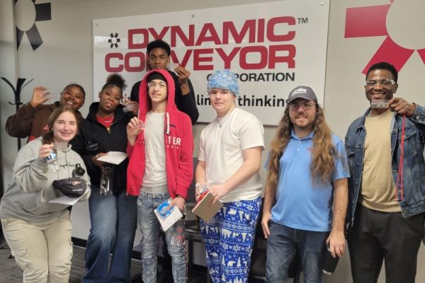 group of Muskegon Community Education students in front of Dynamic COnveyor corp sign