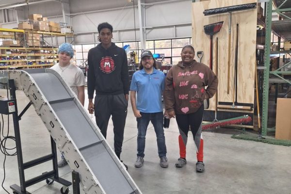 students standing on the dynamic conveyor manufacturing shop floor